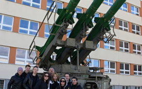 Studenti střední školy z Volyně a jejich učitelé před odpalovacím zařízením s raketami.